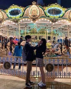 two people standing in front of a merry go round