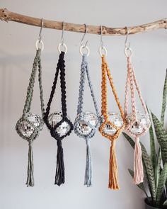 four different colors of macrame and tassels hanging from a tree branch