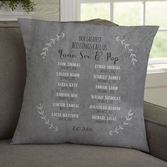 a gray pillow sitting on top of a couch in front of a window with the names of wedding guests