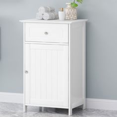 a small white cabinet with towels on top