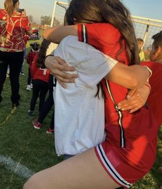 two girls hugging each other on a soccer field