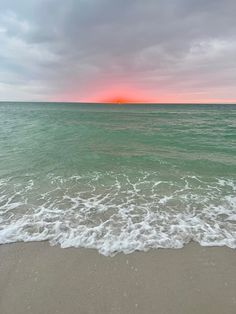 the sun is setting over the water at the beach