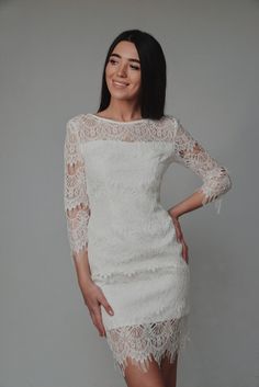 a woman in a white dress posing for the camera with her hands on her hips