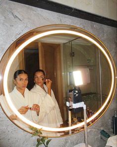 two women standing in front of a mirror