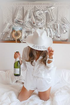 a woman sitting on top of a bed holding a bottle