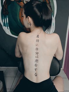 the back of a woman's body with chinese writing on her upper back tattoo