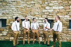 a group of men standing next to each other in front of a stone building with windows