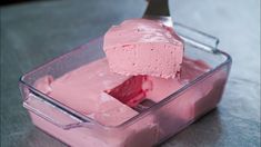 a pink cake in a plastic container with a knife