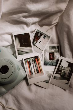 polaroid camera sitting on top of a bed next to four pictures and a pen