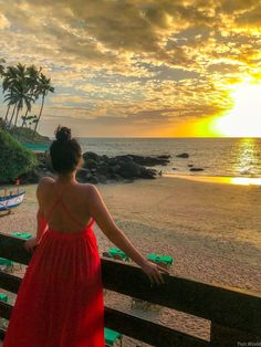 a woman in a red dress looking out at the ocean