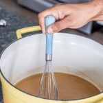 a person mixing something in a yellow pot