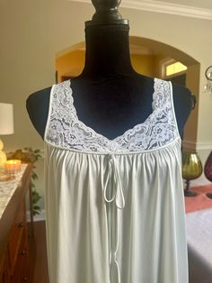 A lovely nightgown with lace trim on the bodice.  The color is somewhere between a very pale blue and light pearl gray.  Lace neckline on the front with a decorative tie at the bustling.  In good vintage condition with no rips or stains.  The bust measures 18 inches from armpit to armpit, laying flat.  55 inches from shoulder to hem, ideal for someone on the taller side.  100% nylon. Size medium Delicate Lace Sleeveless Dress For Loungewear, Feminine Sleeveless Delicate Lace Sleepwear, Feminine Delicate Lace Sleeveless Sleepwear, Sleeveless Summer Sleepwear With Contrast Lace, Feminine Sleeveless Lace Patchwork Sleepwear, Feminine Sleeveless Sleepwear With Lace Patchwork, Sleeveless Nightgown With Delicate Lace For Loungewear, Sleeveless Delicate Lace Nightgown For Loungewear, Lace Nightgown With Lace Trim For Sleep