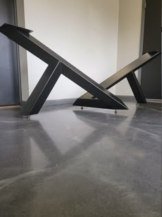 a metal sculpture sitting on top of a floor next to a wall in an empty room