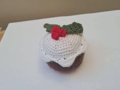 a crocheted cupcake with a red flower on top sitting on a table