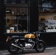 a motorcycle is parked in front of a storefront on the side of the street