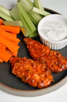 the plate has carrots, celery and chicken wings with ranch dressing on it