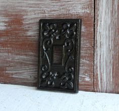 a black light switch cover sitting on top of a white tablecloth next to a wooden door