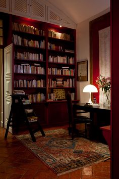 a living room filled with furniture and a book shelf full of books next to a lamp