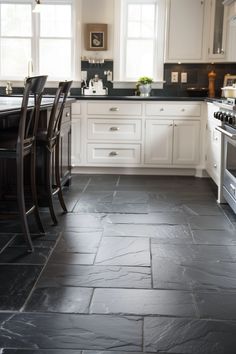 a kitchen with white cabinets and black tile flooring