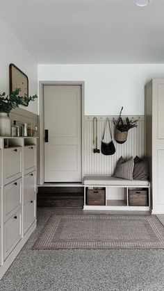 a room with white cabinets and drawers, a bench on the floor and a rug in front of it