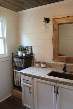 a bathroom sink sitting under a large mirror next to a window in a white room