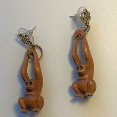 two monkey figurines are hanging from chains on the wall, one is holding an object in its hands