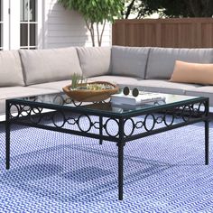 a glass coffee table sitting on top of a blue and white rug next to a couch