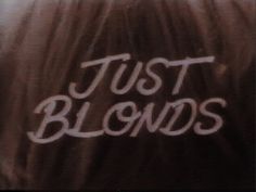 the words just blondes written in white spray paint on top of long brown hair