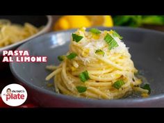 a bowl filled with pasta and garnished with parmesan cheese, lemons and mint