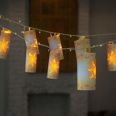 some paper lanterns are hanging from a string with lights on them in front of a fireplace