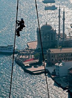 an aerial view of some buildings and boats in the water with one person on a rope