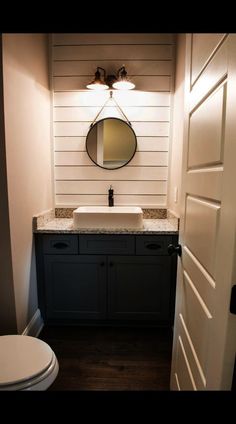 a white toilet sitting next to a sink in a bathroom under a mirror above a vanity