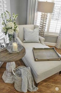 a living room filled with furniture and flowers on top of a coffee table in front of a window