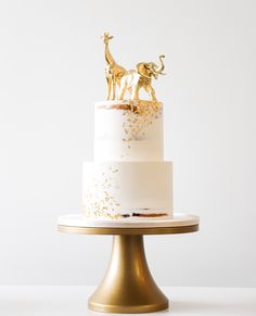 a white and gold cake with two giraffes on top