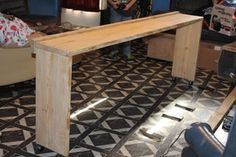 a long wooden table sitting on top of a black and white floor next to a couch