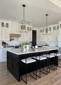 a kitchen with white cabinets and black island