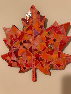 an orange mosaic leaf is hanging on the wall