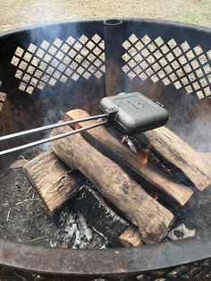 an outdoor grill with logs and tongs cooking on it