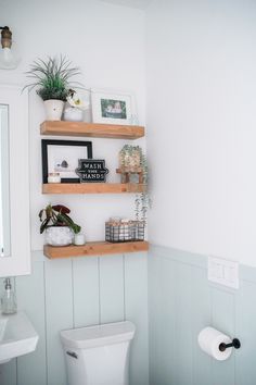 a white toilet sitting next to a wooden shelf filled with potted plants on top of it