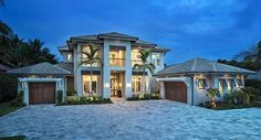 a large house with two garages and palm trees in the front yard at dusk