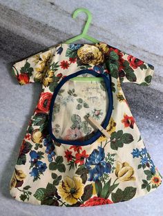 an infant's dress with flowers on it and a magnifying glass in the pocket