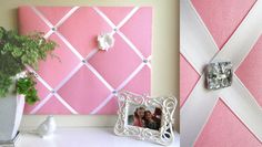 a pink and white photo frame next to a vase with a plant in it on a shelf