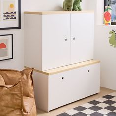 a white cabinet sitting on top of a wooden shelf next to a brown bag in a living room