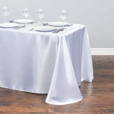 the table is set with white plates and silverware, along with empty wine glasses