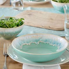 a table set with plates, bowls and silverware