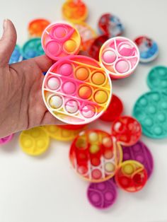 a hand holding a mickey mouse toy in front of many different colored plastic toys on a white surface