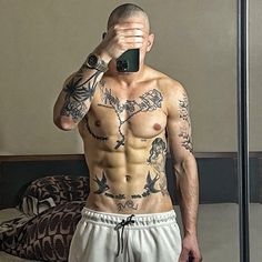 a man taking a selfie in front of a mirror with tattoos on his chest