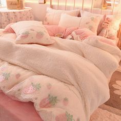 a bed with pink and white comforters, pillows and blankets on top of it