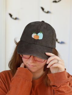 Celebrate the Fall and Halloween seasons with this super comfortable and ultra cute hat featuring either a single orange pumpkin or a trio of pumpkins.  We machine embroider each one just for you. Both designs available on a brown or black hat. 100% cotton pigment dyed twill Unstructured, six-panel, low-profile Pre-curved visor Tri-glide buckle closure All hand-crafted with a special dye and washing process which results in unique variations of color from one hat to the next. Pumpkin Baseball, Fall Cap, Fall And Halloween, Cute Hat, Orange Pumpkin, Fall Accessories, Cute Hats, Black Hat, Pumpkin Orange