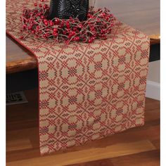 a table topped with a black vase filled with red berries next to a wooden table